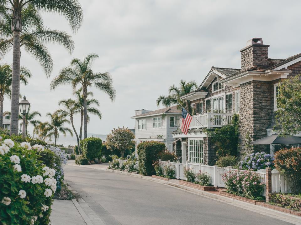 Tree-lined Corona del Mar street with cottage-style homes and gardens